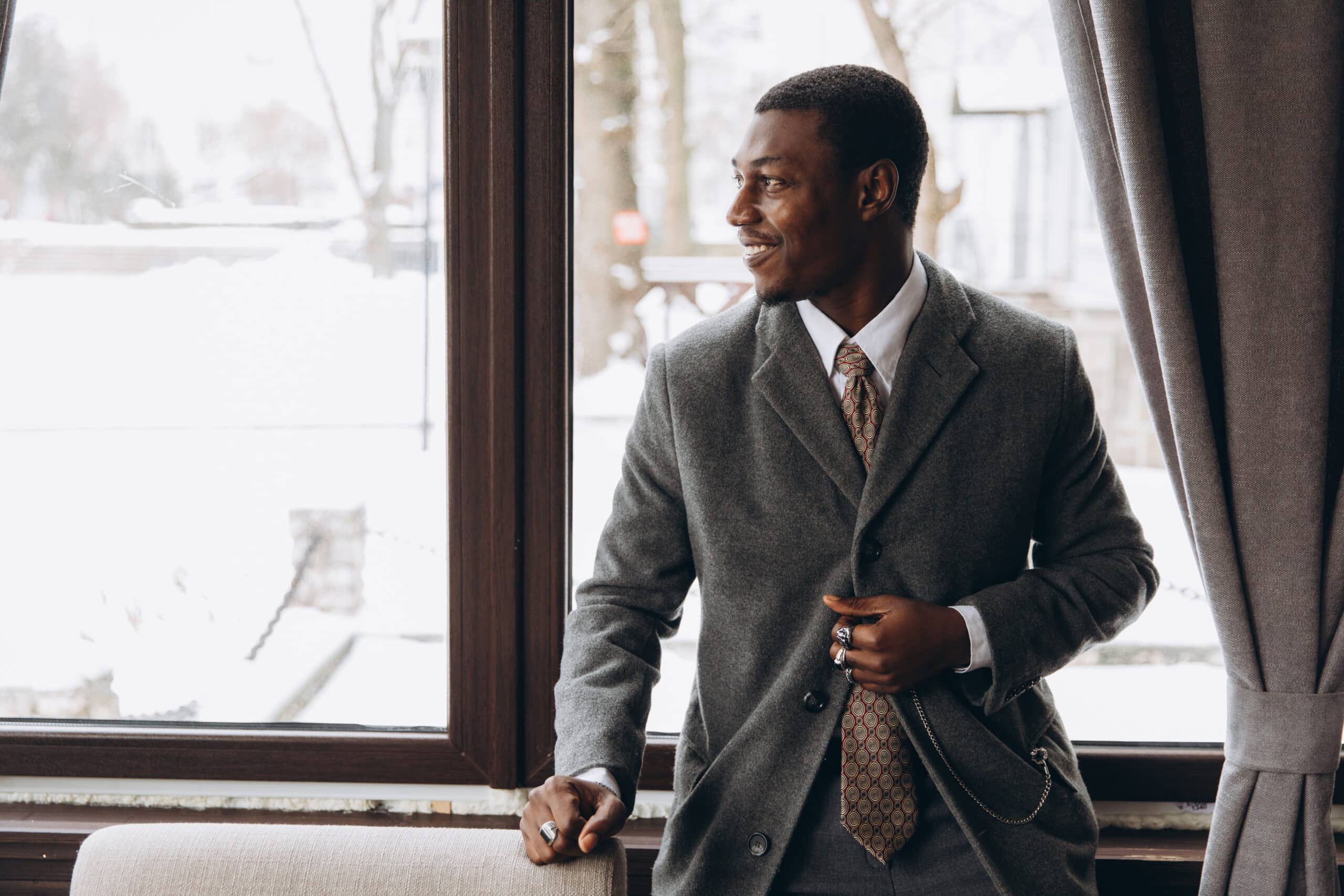 Elegant businessman smiling, looking out winter window